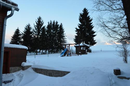 a playground covered in snow next to a house at Mária Kičáková TATRY MKS in Štrba