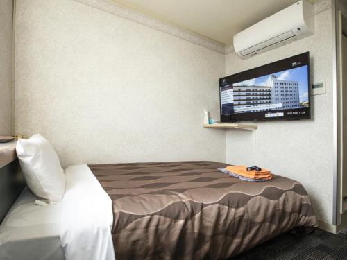 a hotel room with a bed and a flat screen tv at Hotel Fujiyoshi in Beppu