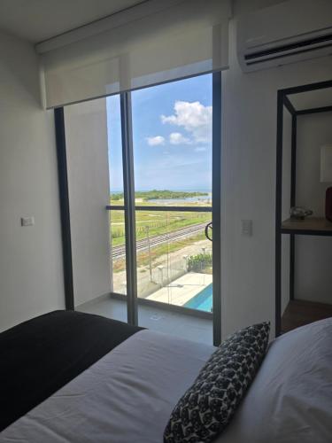 a bedroom with a bed and a large window with a view at Hermosa aparta Suite en Salinas del Mar Club House- By SanStap in Santa Marta