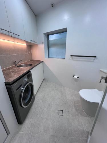 a bathroom with a washing machine and a toilet at Bondi Stylish Bedroom Close to the Beach in Sydney