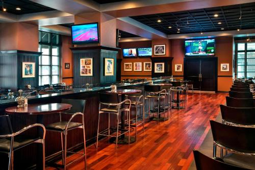 a bar in a restaurant with stools and televisions at Marriott Philadelphia West in West Conshohocken