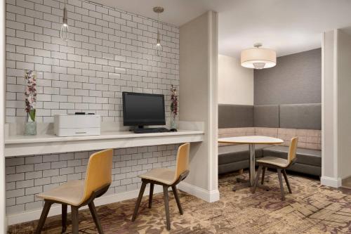 a waiting room with a table and chairs and a tv at Residence Inn by Marriott Buffalo Galleria Mall in Cheektowaga
