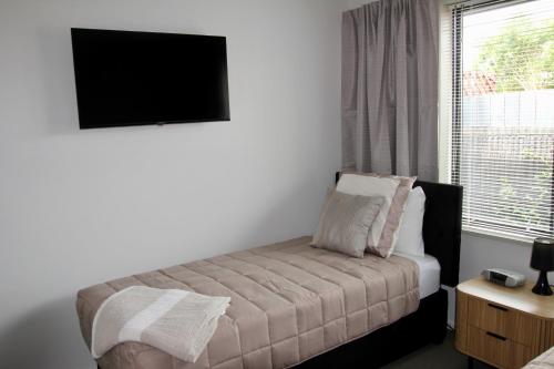 a bedroom with a bed and a tv and a window at Third St Studio in Christchurch