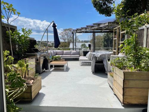 a patio with a couch and a table and some plants at Comfortable townhouse with aircon, huge balcony & hot tub in Auckland