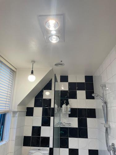 a bathroom with a shower and a black and white checkered floor at Comfortable townhouse with aircon, huge balcony & hot tub in Auckland
