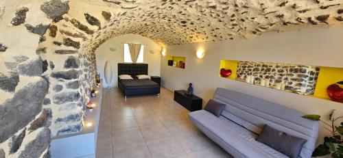 un salon avec un canapé et un mur en pierre dans l'établissement Logement Entier, à Saint-Jean-Lachalm