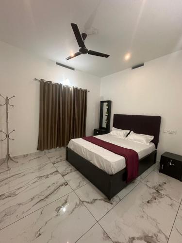 a bedroom with a bed and a ceiling fan at Homie Hub in Meppādi