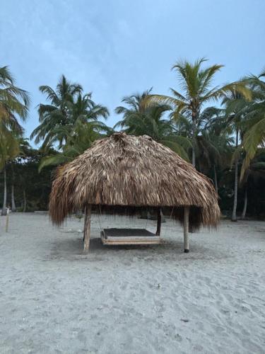a straw hut on a beach with palm trees at Hotel Playa Bonita Tayrona in Buritaca