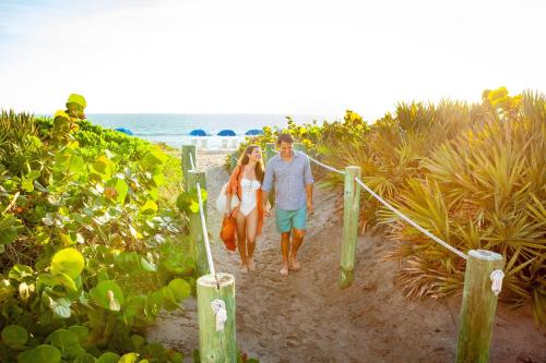 a man and a woman walking down a path on the beach at Marriott Hutchinson Island Beach Resort, Golf & Marina in Stuart