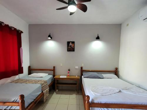 a bedroom with two beds and a ceiling fan at Ometepe House in Moyogalpa