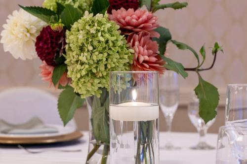 a vase with a candle and flowers on a table at Pittsburgh Marriott City Center in Pittsburgh