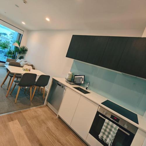 a kitchen with a counter and a table with chairs at Auckland Birkenhead BNB in Auckland