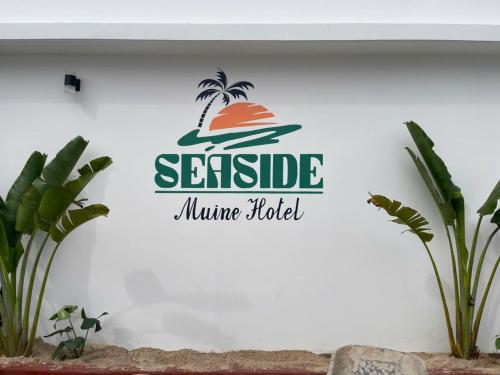 a sign on a wall with a palm tree on it at Seaside Mui Ne Hotel in Mui Ne