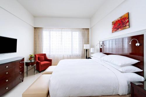 a bedroom with a large white bed and a red chair at Guyana Marriott Hotel Georgetown in Georgetown
