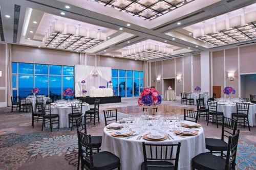 a banquet hall with white tables and chairs and a piano at Guyana Marriott Hotel Georgetown in Georgetown
