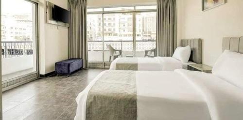Una habitación de hotel con dos camas y balcón. en Magic Waves Hotel Aqaba, en Áqaba