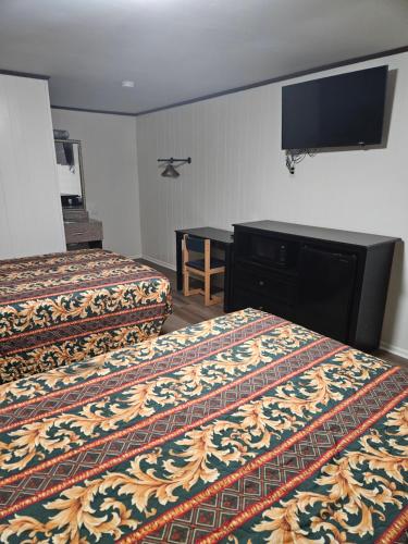 a hotel room with two beds and a flat screen tv at Traveler's Inn in Roanoke