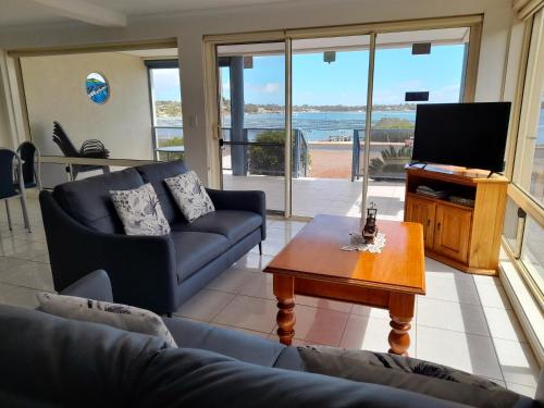 a living room with a couch and a tv and a table at Ambience Apartments 1 in Coffin Bay