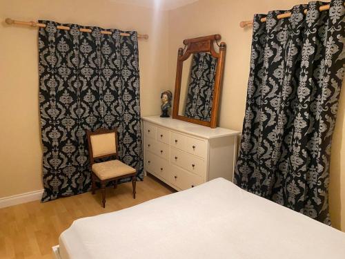 a bedroom with a bed and a mirror and a chair at An Teach Tykillen Cosy Home in Limerick