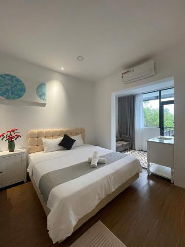 a bedroom with a large white bed and a desk at The Dreamers Homestay in Hue