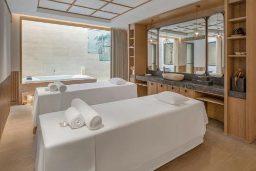 a bathroom with two beds and a sink and a tub at JW Marriott Goa in Vagator