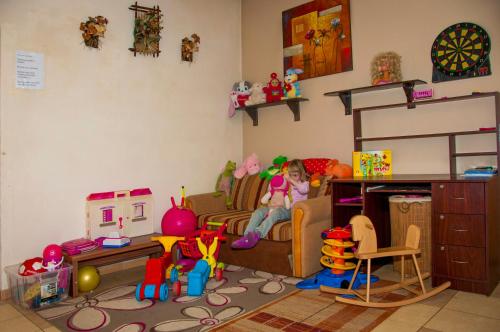 a little girl sitting on a couch in a room filled with toys at Penzión ZIVKA in Závažná Poruba