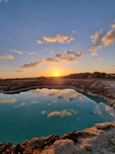 a sunset over a pool of water in the desert at فندق النخيل in Siwa