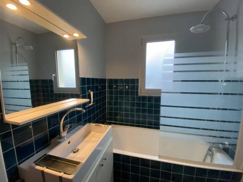 une salle de bain avec une baignoire, un lavabo et un miroir dans l'établissement Appartement rénové à 20m de la plage Trestraou, 2 ch, court séjour possible, animal accepté - FR-1-368-444, à Perros-Guirec
