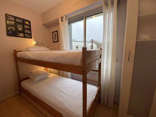 deux lits superposés dans une chambre avec fenêtre dans l'établissement Appartement rénové à 20m de la plage Trestraou, 2 ch, court séjour possible, animal accepté - FR-1-368-444, à Perros-Guirec