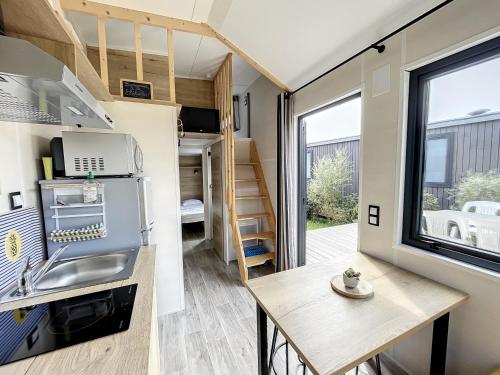 une petite cuisine et un coin repas dans une petite maison dans l'établissement Tiny House cosy près de la plage avec piscine et parking - FR-1-361A-94, à Jullouville