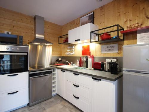 une cuisine avec des armoires blanches et des appareils en acier inoxydable dans l'établissement Chalet au Mont-Dore, 8 pers, 3 ch, animaux admis, parking, terrasse, proche centre - FR-1-608-281, à Mont-Dore