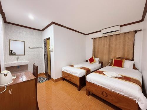 a hotel room with two beds and a sink at Vangvieng Sisavang Mountain View Hotel in Vang Vieng