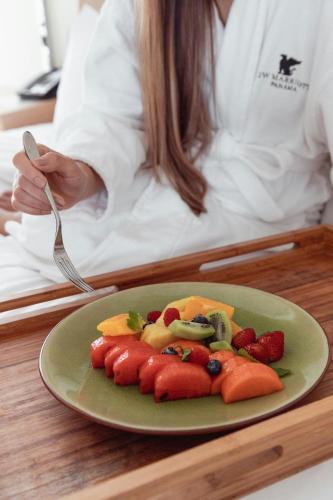 a person sitting at a table with a plate of fruit at JW Marriott Panama in Panama City