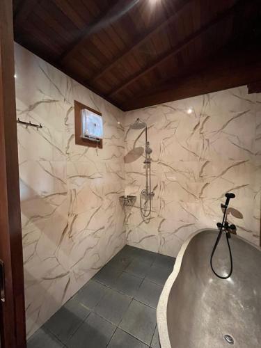 a bathroom with a tub and a tv on the wall at Villa Gong bali in Ubud