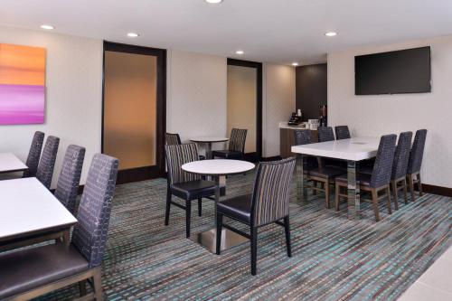 a dining room with tables and chairs and a flat screen tv at Residence Inn by Marriott Cedar Rapids South in Cedar Rapids