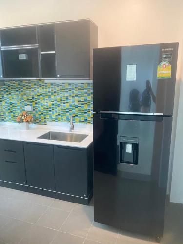 a kitchen with a refrigerator and a sink at Phuket Mali house in Ban Sam Kong