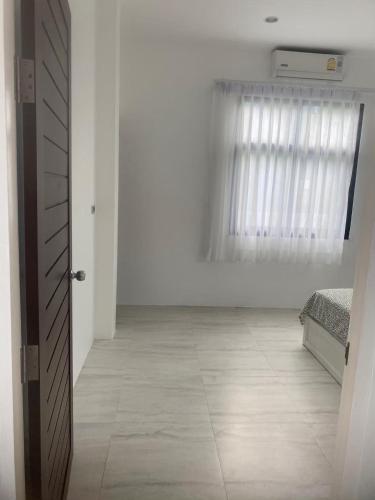 a white room with a bed and a window at Phuket Mali house in Ban Sam Kong