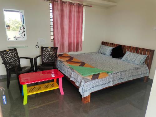 a bedroom with a bed and a table and chairs at SHIVADIVYA Homestay Hampi in Hampi
