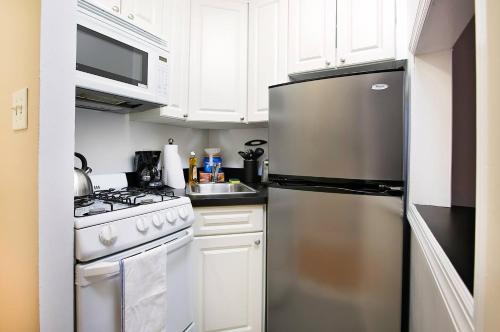 a kitchen with white cabinets and a stainless steel refrigerator at Bright Studio in Central NYC in New York