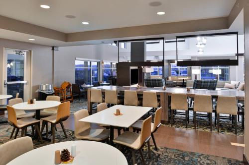 a dining room with tables and chairs and windows at Residence Inn by Marriott Coralville in Coralville