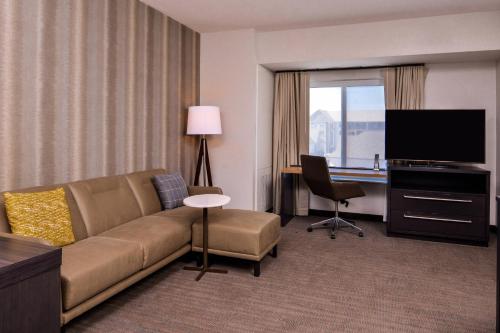 a living room with a couch and a television in a hotel room at Residence Inn by Marriott Charlotte Steele Creek in Charlotte