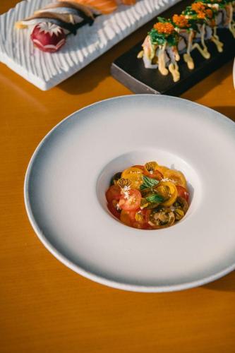 a white plate with a dish of food on a table at JW Marriott Hotel Hanoi in Hanoi