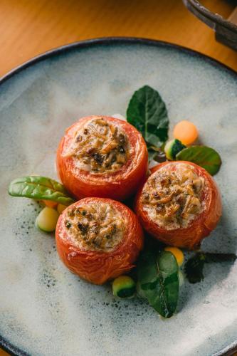 two tomatoes on a plate with leaves on a table at JW Marriott Hotel Hanoi in Hanoi