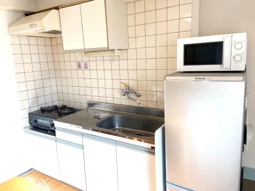 a small kitchen with a sink and a microwave at HARUKAZE HOUSE in Tokyo