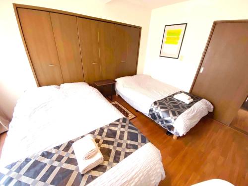 a room with two beds and a suitcase in it at HARUKAZE HOUSE in Tokyo