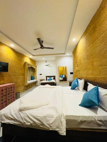 a bedroom with a large white bed with blue pillows at Silent Sands Jaisalmer in Jaisalmer