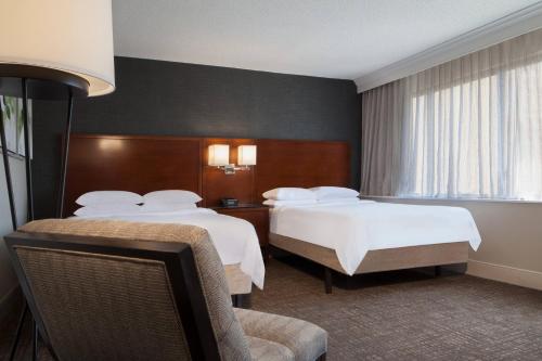 a hotel room with two beds and a chair at Marriott Raleigh Durham Research Triangle Park in Durham