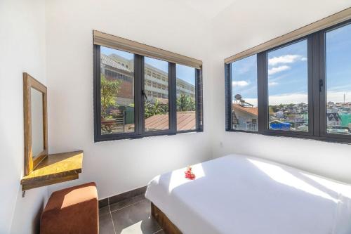 a bedroom with a white bed and windows at D View Apartment in Da Lat