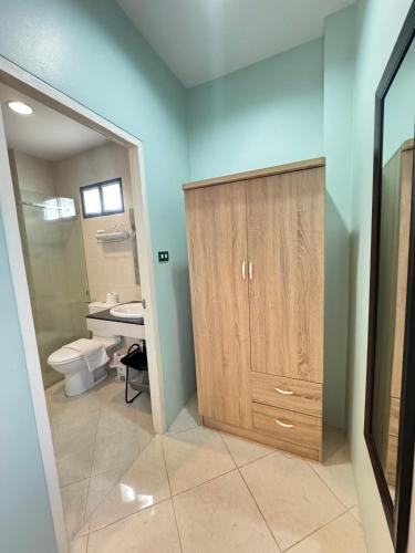 a bathroom with a toilet and a wooden cabinet at Venice Hotel Hua Hin in Hua Hin