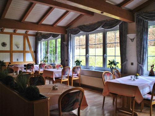 un comedor con mesas, sillas y ventanas en Waldhotel Einstein, en Kirchhundem